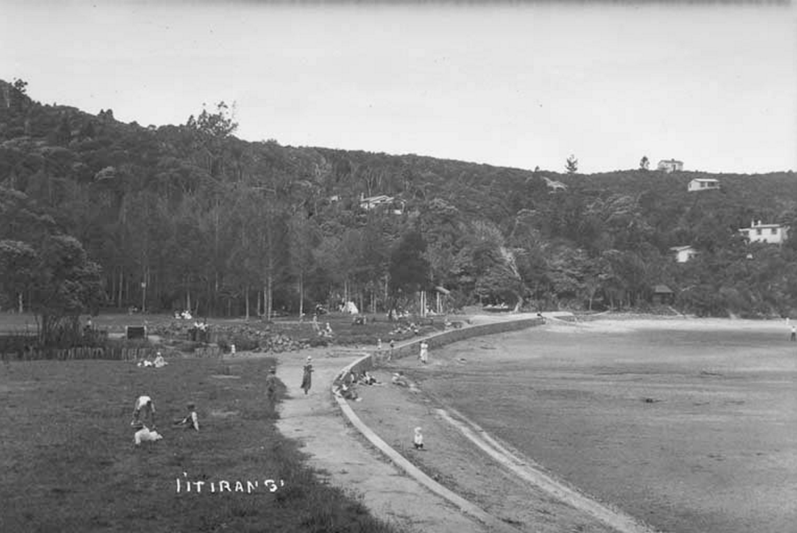 Looking north east along Titirangi beach showing baches in bush clad hills behind.1934. Sir George Grey Special Collections, Auckland Libraries.